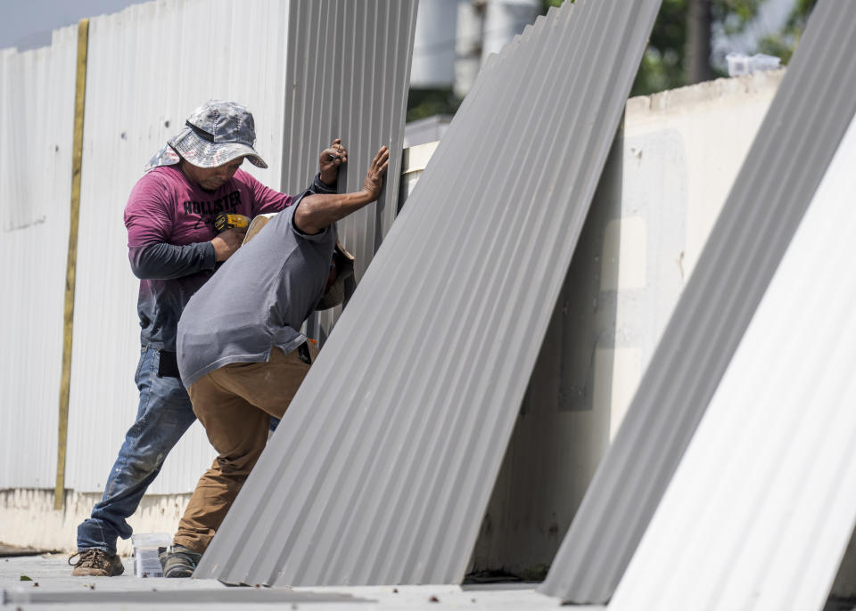 Laundry-4U employees install new sheet metal siding along the roof of the business, Saturday, May 18, 2024, in Houston. (Jason Fochtman/Houston Chronicle via AP)