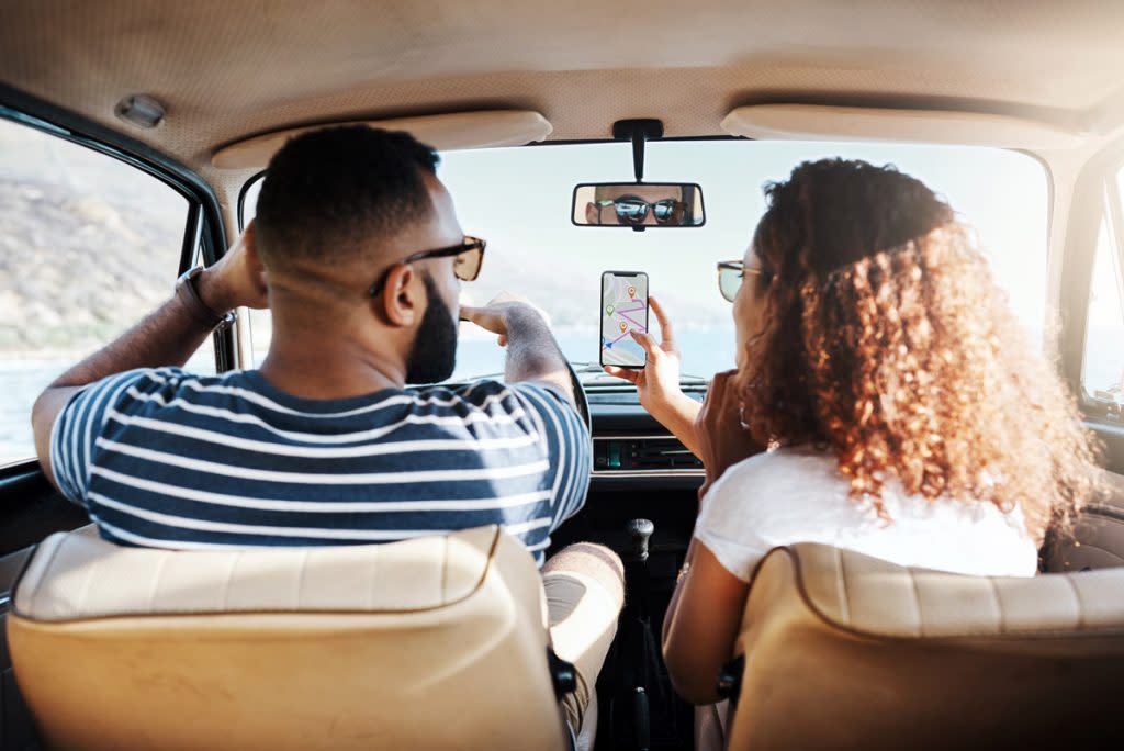 A couple use their navigation system on their phone while driving.