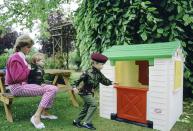 <p>In the garden of her home in Highgrove, Princess Diana watches her sons play with a playhouse in 1986. </p>