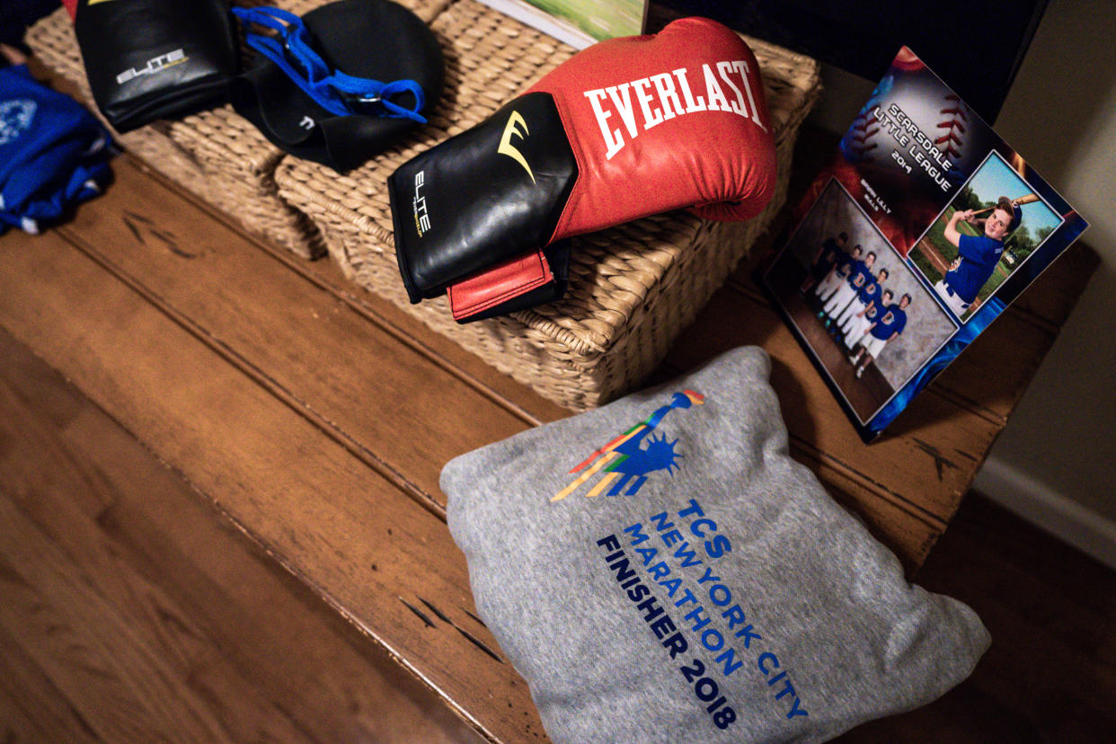 Brian Lilly Jr.'s swim cap and goggles, boxing gloves, New York City Marathon sweatshirt and Little League photos are displayed in Brenda and Brian Lilly's home, Thursday, Oct. 13, 2022, in Easton, Conn. Brian Lilly Jr., 19, who committed suicide on Jan. 4, 2021, was a rower at University of California San Diego. The Lillys have filed a wrongful death lawsuit against the university and the rowing coach, Geoff Bond, who is no longer with the school. (AP Photo/Julia Nikhinson)