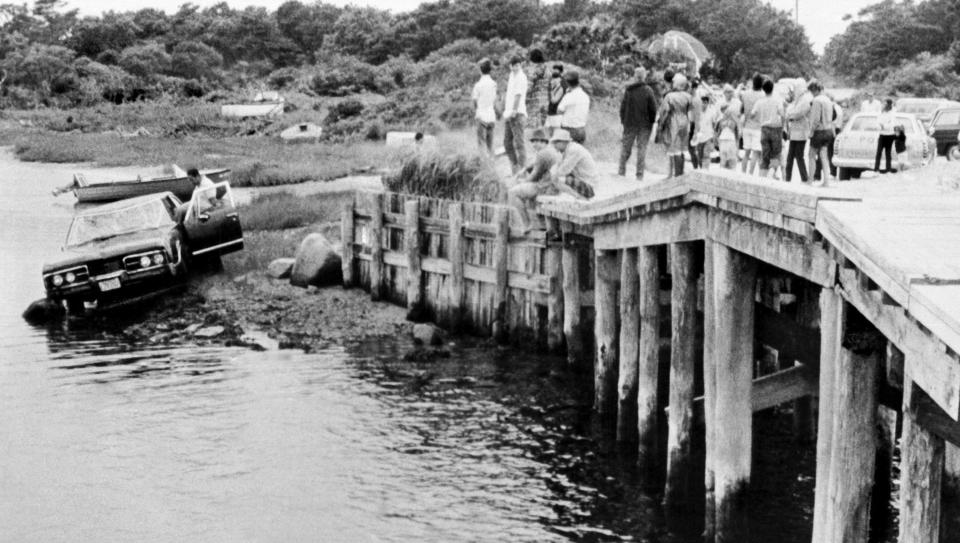 FILE - In this July 19, 1969 file photograph, crowds watch as U.S. Sen. Edward Kennedy's car is pulled from water at the Dyke Bridge in Edgartown, Mass. It's been 50 years since the fateful automobile accident that killed a woman and thwarted Kennedy's presidential aspirations. (AP Photo, File)