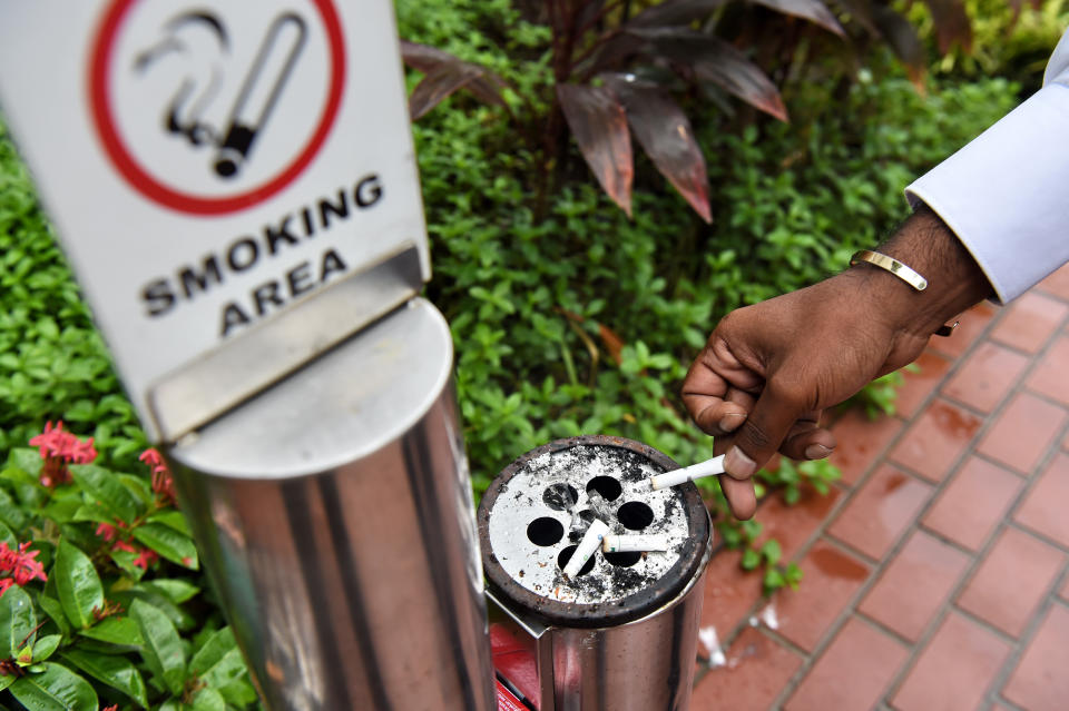 A man smokes at a designated smoking area next to an office building in Singapore on 27 November, 2017. (PHOTO: AFP via Getty Images)