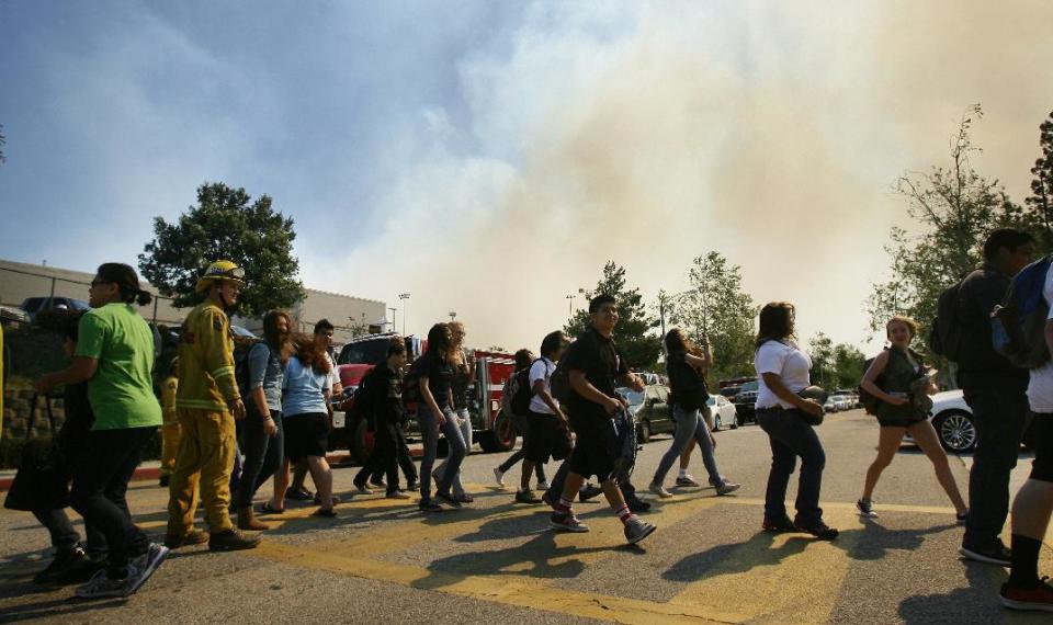 Students from Los Osos High School are evacuated from the school as a brush fire burning in Day Creek near the Etiwanda Preserve in Rancho Cucamonga, Calif., on Wednesday, April 30, 2014. Fire officials say winds gusting to 60 mph are pushing the flames through the foothills of the San Bernardino Mountains east of Los Angeles, although no homes are in immediate danger. Several neighborhoods and at least seven schools in Rancho Cucamonga have been evacuated. There’s no word on what sparked the blaze but it comes in the midst of a heat wave that’s created extreme fire danger. (AP Photo/The Press-Enterprise, Stan Lim) MAGS OUT; MANDATORY CREDIT