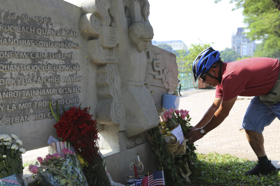 In this Aug. 27, 2018, file photo, Pham Van Khanh, a 62-year-old retiree, lays flowers at the monument of Senator John McCain in Hanoi, Vietnam. The monument was erected by Vietnamese authority to mark the day when McCain's plane, a Major in the U.S. Navy was shot down in 1967. Vietnam has been paying respect to McCain who died on Saturday. (AP Photo/Tran Van Minh, File)