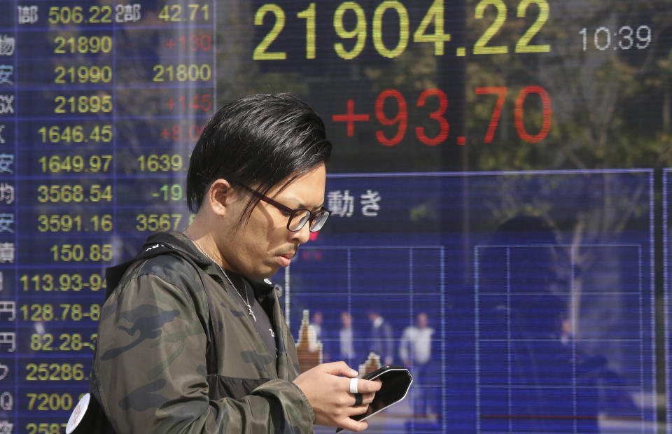 A man walks by an electronic stock board of a securities firm in Tokyo, Wednesday, Nov. 14, 2018. Asian shares were mostly lower Wednesday, after the steepest drop in oil prices in more than three years put investors in a selling mood on Wall Street. (AP Photo/Koji Sasahara)