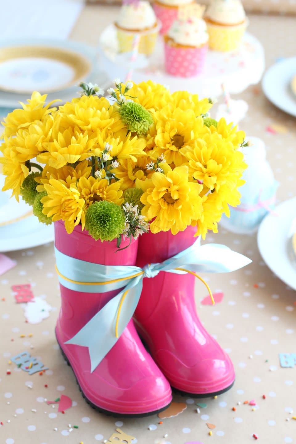 using rain boots as a vase for a bouquet of flowers is a great baby shower idea