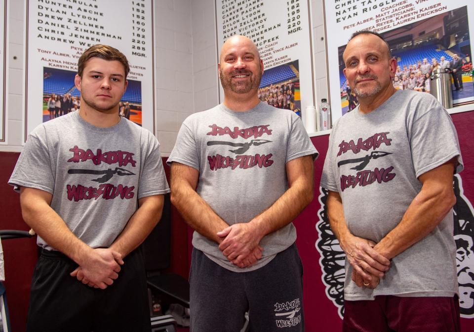 Dakota assistant coach Josh Alber, left, new head coach Matt Jacobs, center, and former head coach Pete Alber pose in the practice room on Thursday, Dec. 2, 2021, at Dakota High School.