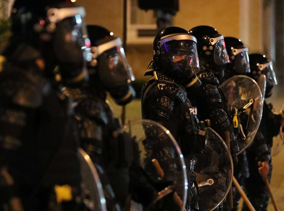 Police officers in full riot gear block off a section of High Street near the Harold K. Stubbs Justice Center in Akron late Sunday night.