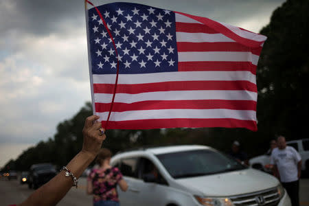 A woman waves the U.S. flag as samaritans offer water and food to residents who returned to their homes flooded by Tropical Storm Harvey in Houston, Texas, U.S. September 4, 2017. REUTERS/Adrees Latif