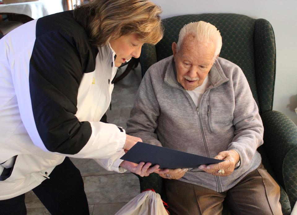 Angels 4 Vets volunteer and Navy veteran Donna Nuechterlein  gives Air Force veteran Emil Skinlo a letter of  achievement for his patriotism and duty.