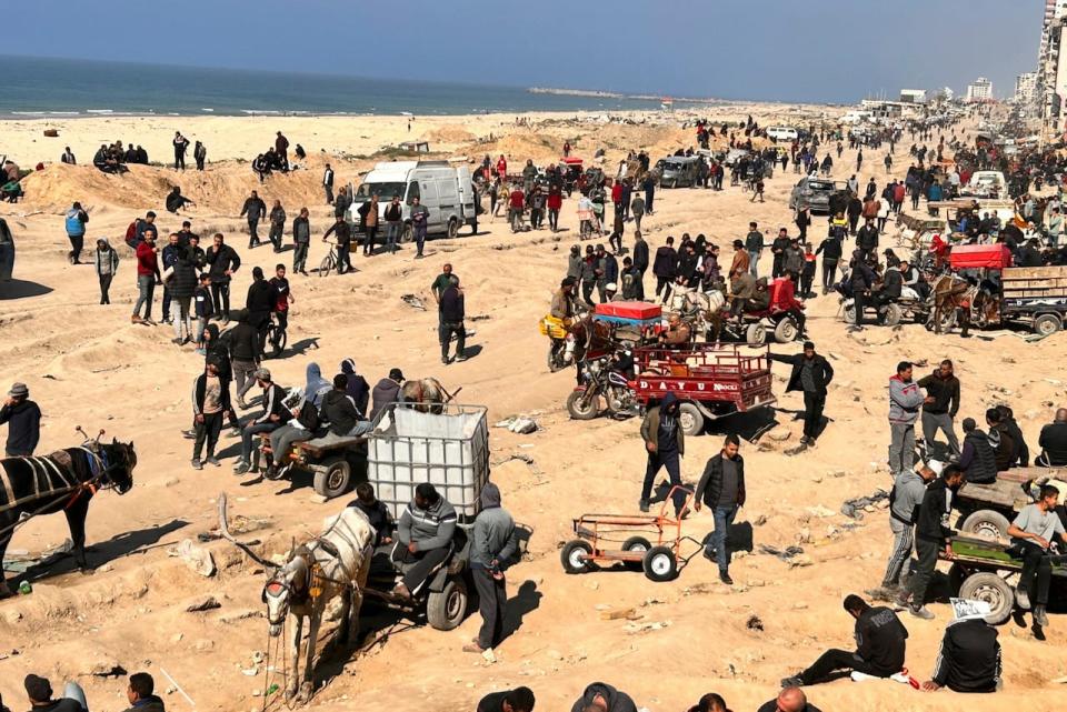 Palestinians wait for humanitarian aid on a beachfront in Gaza City on Sunday, Feb. 25, 2024. (Mahmoud Essa/The Associated Press - image credit)