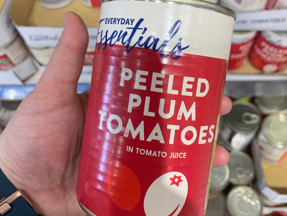 hand holding a can of tinned tomatoes at aldi