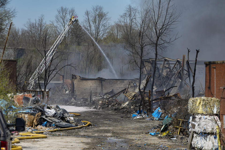 Firefighters pour water on an industrial fire in Richmond, Ind., Wednesday, April 12, 2023. Authorities urged people to evacuate if they live near the fire. The former factory site was used to store plastics and other materials for recycling or resale. (AP Photo/Michael Conroy)