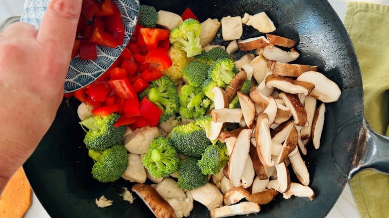 adding broccoli, mushrooms and vegetables to wok