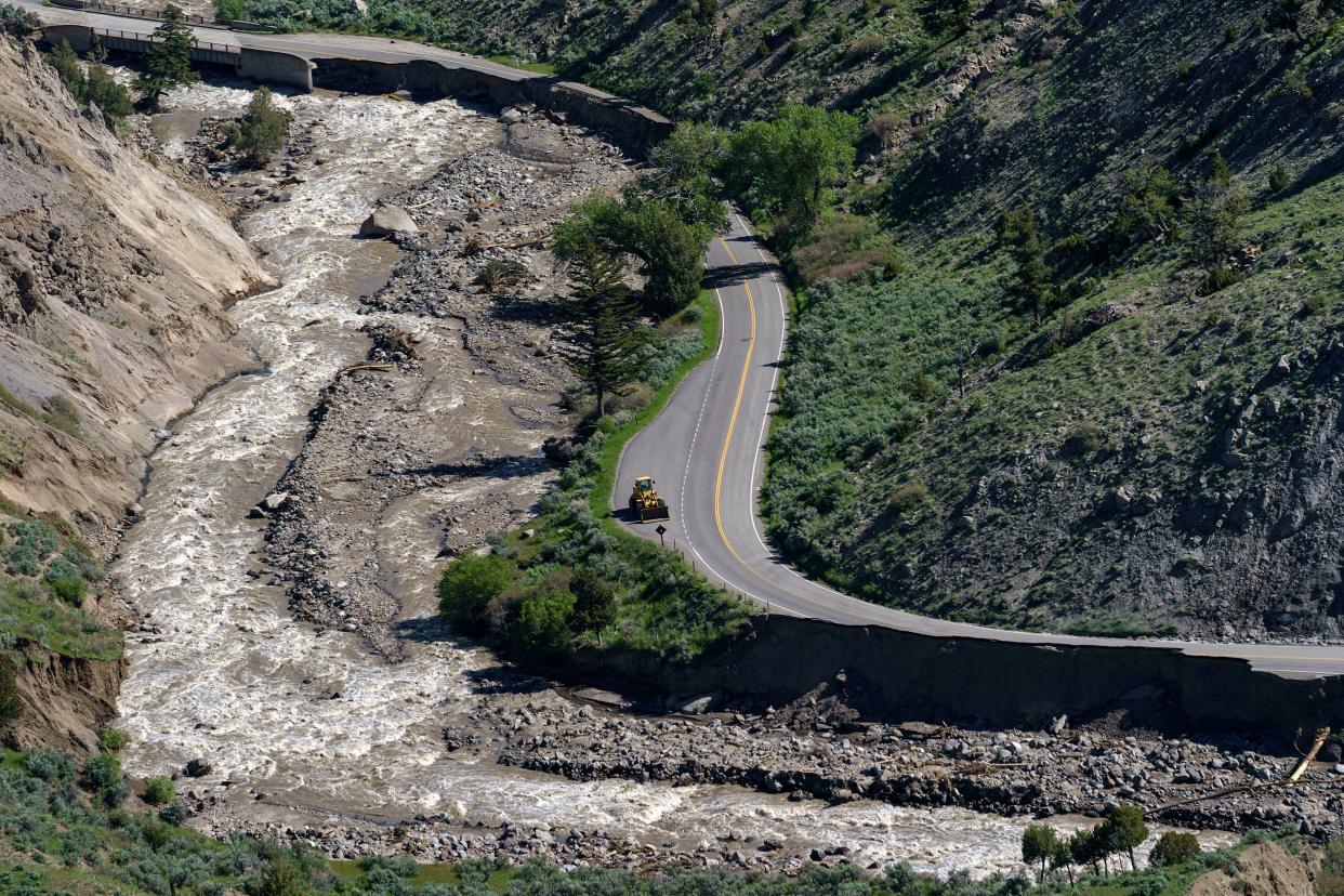 A bulldozer sits on North Entrance Road surrounded by sections washed away by recent floodwaters at Yellowstone National Park in Gardiner, Mont., Thursday, June 16, 2022.