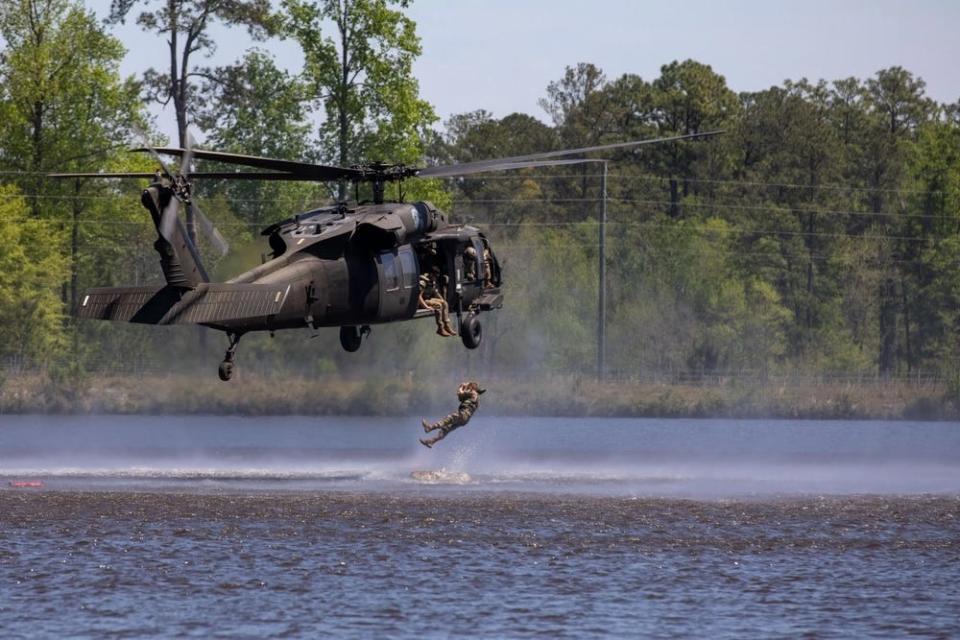 Two US Army Soldiers descend into the water from a UH-60A Black Hawk during the Helocast event.