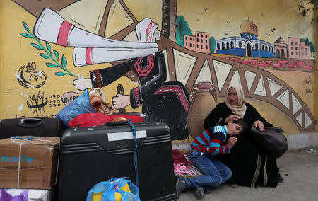 A woman sits with her son as they wait for a travel permit to cross into Egypt through the Rafah border crossing after it was opened by Egyptian authorities for humanitarian cases, in the southern Gaza Strip February 8, 2018. REUTERS/Ibraheem Abu Mustafa