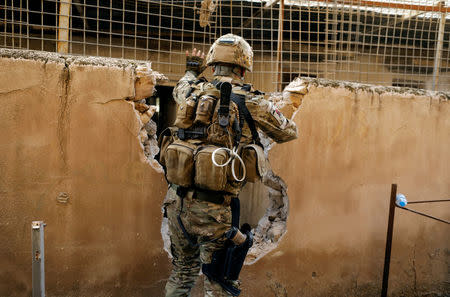 An Iraqi rapid response member moves from house to house through a hole in a wall to avoid being hit by Islamic State snipers in western Mosul, Iraq March 9, 2017. REUTERS/Zohra Bensemra