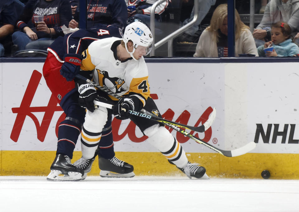 Pittsburgh Penguins forward Danton Heinen, right, reaches for the puck in front of Columbus Blue Jackets defenseman Vladislav Gavrikov during the second period of an NHL hockey game in Columbus, Ohio, Saturday, Oct. 22, 2022. (AP Photo/Paul Vernon)