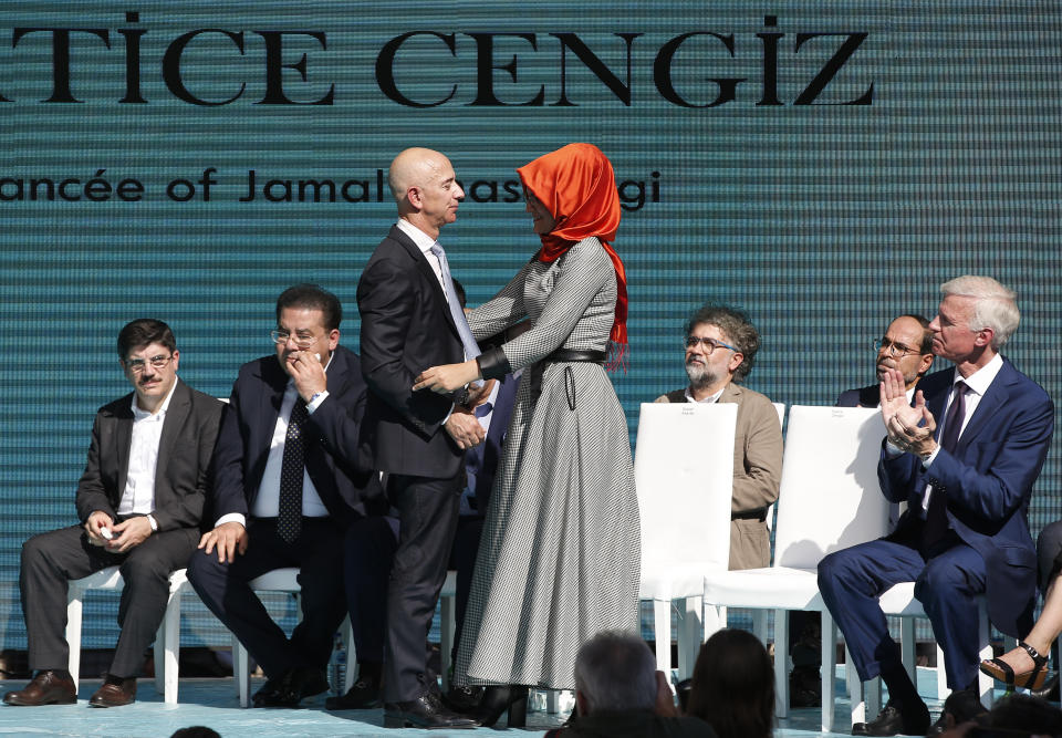 Washington Post owner Jeff Bezos, left, talks to Hatice Cengiz, right, the fiancee of slain Saudi journalist Jamal Kashoggi, during a ceremony near the Saudi Arabia consulate in Istanbul, marking the one-year anniversary of his death, Wednesday, Oct. 2, 2019. A vigil was held outside the consulate building Wednesday, starting at 1:14 p.m. (1014 GMT) marking the time Khashoggi walked into the building where he found tragic death. (AP Photo/Lefteris Pitarakis)