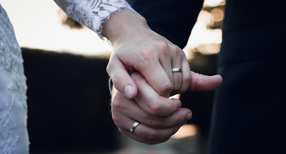 A couple holding hands at their wedding.