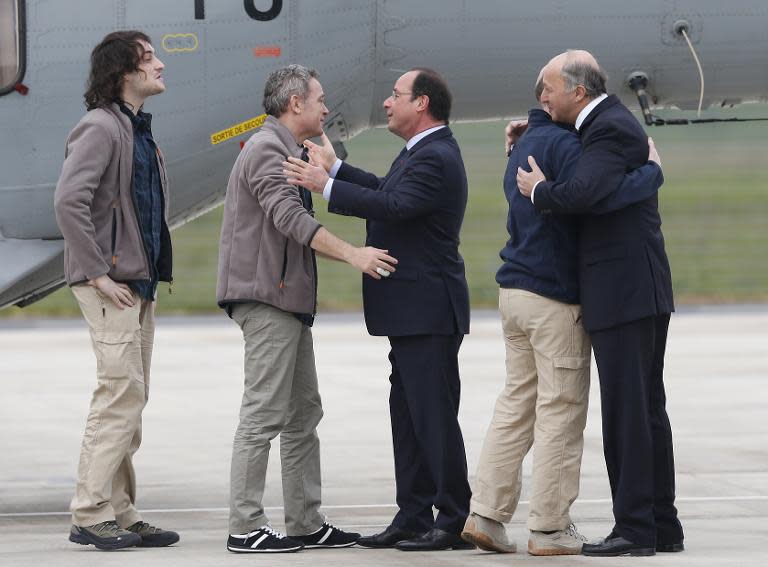 French President Francois Hollande (C) and French Foreign Minister Laurent Fabius (R) welcome French journalists Nicolas Henin (2R), Didier Francois (2L) and Edouard Elias at the Villacoublay air base southwest of Paris on April 20, 2014