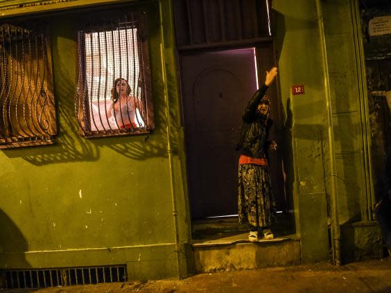 A transgender woman looks out of a window and a woman reacts as women’s rights activists march through Taksim Square to protest against gender violence (AFP/Getty)