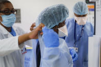 FILE - In this May 27, 2020, file photo, medical personnel adjust their personal protective equipment while working in the emergency department at NYC Health + Hospitals Metropolitan in New York. The personal protective gear that was in dangerously short supply during the initial weeks of the coronavirus crisis in the U.S. is running out again as the virus resumes its rapid spread and the number of hospitalized patients climbs. (AP Photo/John Minchillo)