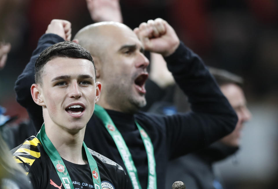 Manchester City's Phil Foden celebrates flanked by Manchester City's head coach Pep Guardiola after winning the English League Cup Final soccer match between Aston Villa and Manchester City, at Wembley stadium, in London, England, Sunday, March 1, 2020. (AP Photo/Alastair Grant)