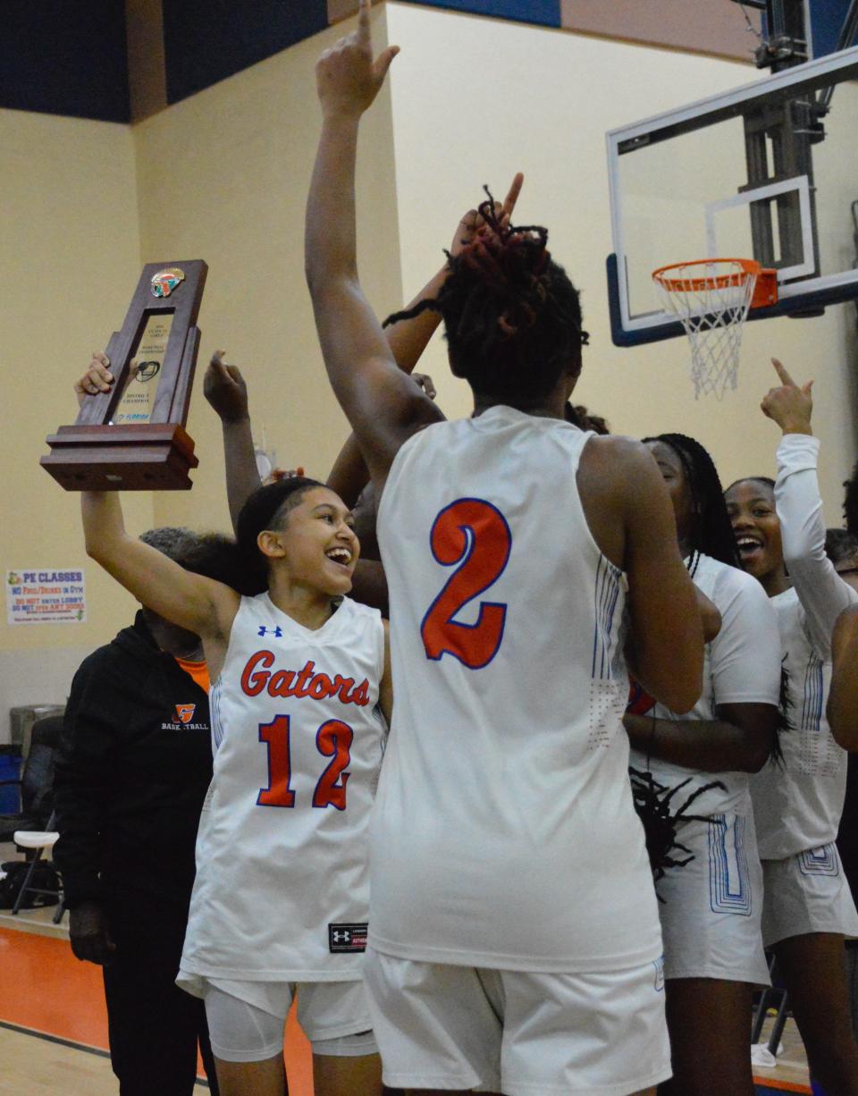 Palm Beach Gardens' Azariah Marrero proundly holds up the district championship trophy after her team's win against Centennial on Feb. 9, 2024.