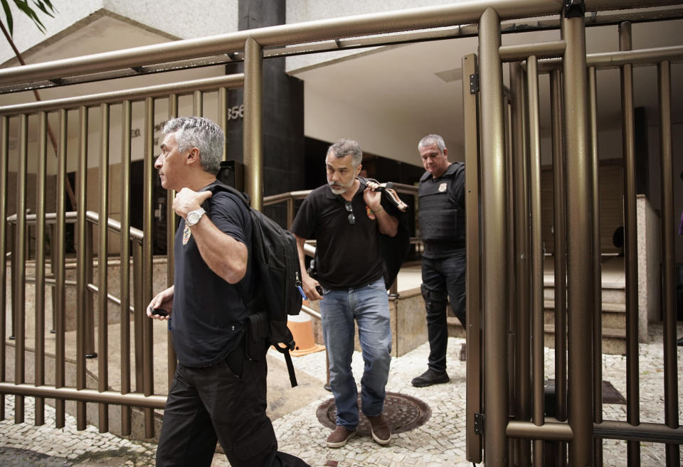 Federal police officers leave a residential building carrying seized documents from suspects under investigation for kickbacks and money laundering, in Rio de Janeiro, Brazil, Tuesday, Nov. 19, 2019. Brazilian police are seeking the arrest of Paraguay's ex-President Horacio Cartes as part of the investigation. (AP Photo/Silvia Izquierdo)