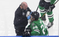 A trainer tends to Dallas Stars' Roope Hintz (24), who had hit the boards during the second period against the Tampa Bay Lightning in Game 4 of the NHL hockey Stanley Cup Final, Friday, Sept. 25, 2020, in Edmonton, Alberta. (Jason Franson/The Canadian Press via AP)