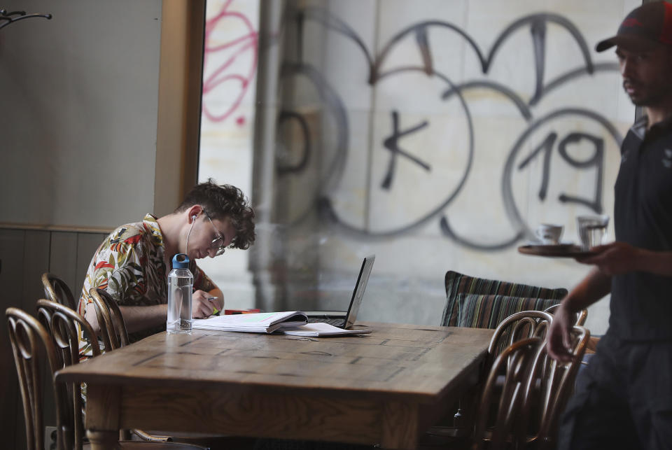A Polish man works in a cafe in Warsaw, Poland, Thursday, Aug. 1, 2019. Poland on Thursday scrapped its personal income tax for young employees earning less than dollars 22,000 a year, as part of a drive to reverse a brain drain and demographic decline that's dimming the prospects of a country that is otherwise experiencing strong economic growth.(AP Photo/Czarek Sokolowski)
