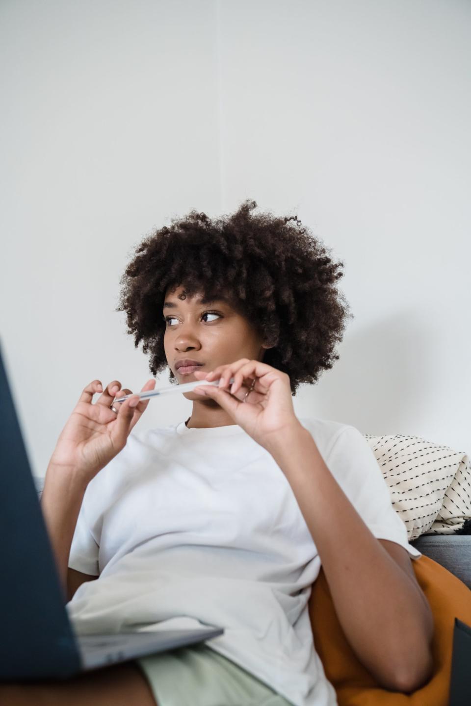 Black woman thinking with a pen in her hand