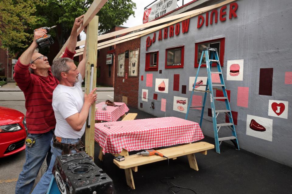 Carpenters Tom Percoco, left, and Dan Mercier build an outdoor dining area at the Red Arrow Diner in Manchester, N.H., on May 18, 2020. The diner, which closed their inside dining area in March due to business restrictions created by the COVID-19 virus outbreak, expected to open their outdoor area for customers later in the day Restaurants across New Hampshire reopened to outdoor table service on Monday.