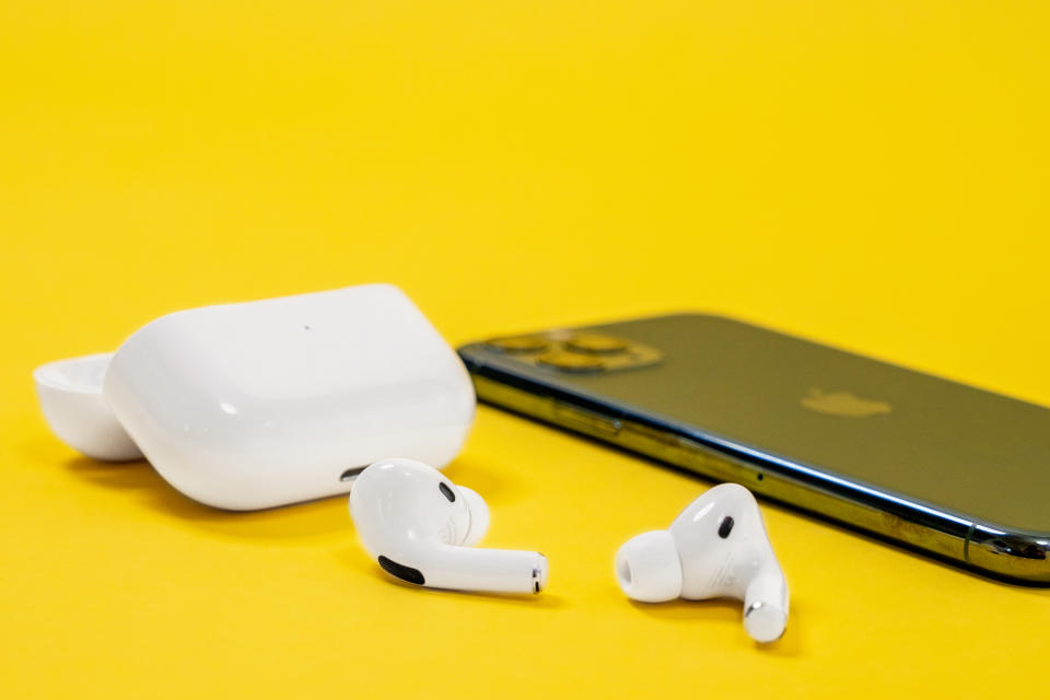 Apple iPhone 11 Pro Smartphone in nachtgrüner Farbe und kabellose Kopfhörer mit offenem Ladekoffer für aktiven Lebensstil auf gelbem Hintergrund, Draufsicht, Kopierraum.