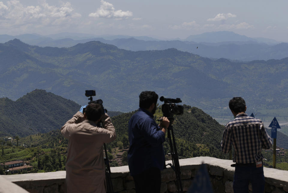 Cameramen film the Indian controlled Kashmiri area from a hilltop post in Chiri Kot sector near the Line of Control, that divides Kashmir between Pakistan and India, Wednesday, July 22, 2020. Villagers living along a highly militarized frontier in the disputed region of Kashmir have accused India of "intentionally targeting" civilians, but they are vowing that they would never leave their areas. Villagers say the fear of death is no longer present in their hearts after spending so many years in a state of shock and uncertainty. (AP Photo/Anjum Naveed)