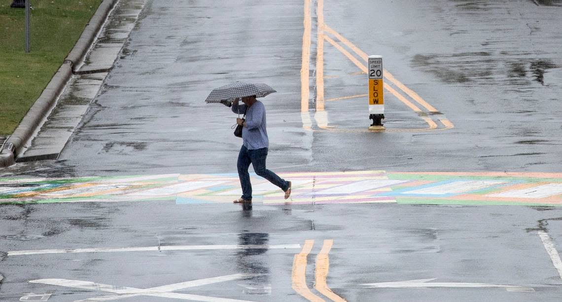 A pedestrian takes shelter under an umbrella while crossing Blackwell Street in Durham, N.C. as the Triangle feels the effects of Hurricane Ian on Friday, Sept. 30, 2022.