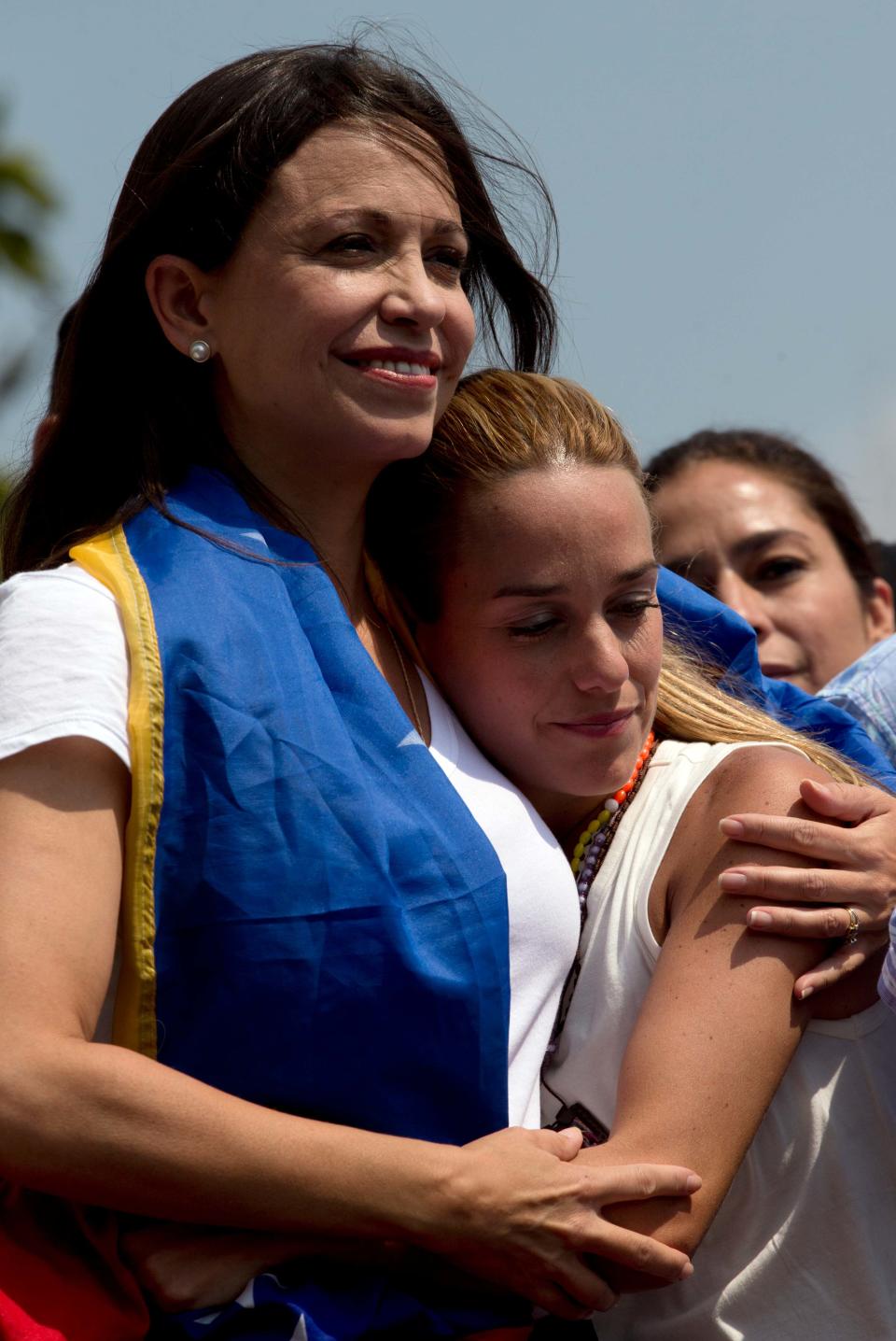 Leading opposition politician Maria Corina Machado, left, embraces Lilian Tintori, wife of jailed opposition leader Leopoldo Lopez, during a rally in Caracas, Venezuela, Wednesday, March 26, 2014. The head of Venezuela's congress, Diosdado Cabello, said Monday that Machado, who was stripped of her parliament seat, violated the constitution by addressing the Organization of American States last week at the invitation of Panama, which ceded its seat at the Washington-based group group so she could provide regional diplomats with a firsthand account of the unrest. (AP Photo/Fernando Llano)