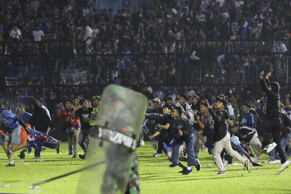 Soccer fans enter the pitch during a clash between supporters at Kanjuruhan Stadium in Malang, East Java, Indonesia, Saturday, Oct. 1, 2022. Panic following police actions left over 100 dead, mostly trampled to death, police said Sunday. (AP Photo/Yudha Prabowo)