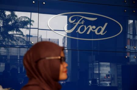 A woman stands near a Ford logo at Central Jakarta Ford Dealer in Jakarta, Indonesia, June 27, 2016. REUTERS/Beawiharta