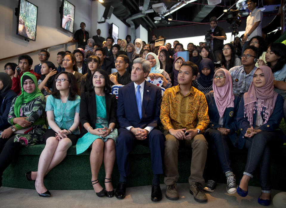 Secretary of State John Kerry sits with a group of students as he is introduced to deliver a speech on climate change on Sunday, Feb. 16, 2014, in Jakarta. Climate change may be the world's "most fearsome" weapon of mass destruction and urgent global action is needed to combat it, Kerry said on Sunday, comparing those who deny its existence or question its causes to people who insist the Earth is flat. (AP Photo/ Evan Vucci, Pool)