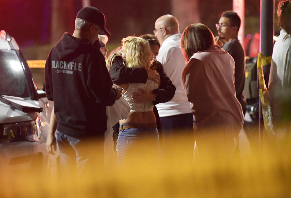 People comfort each other as they stand near the scene.