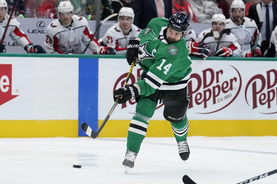 Dallas Stars left wing Jamie Benn (14) takes a shot in the first period of an NHL hockey game against the Washington Capitals in Dallas, Friday, Jan. 28, 2022. (AP Photo/Tony Gutierrez)