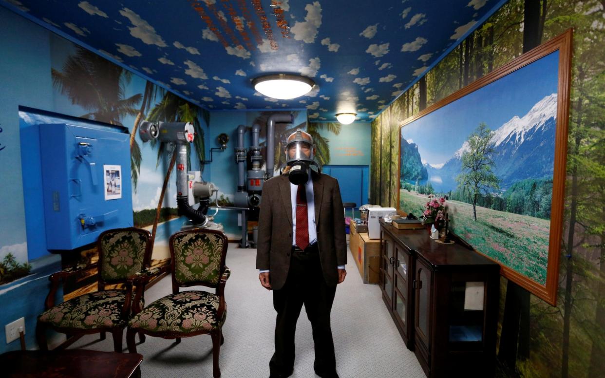 Seiichiro Nishimoto, CEO of Shelter Co., poses wearing a gas mask at a model room for the company's nuclear shelters in the basement of his house in Osaka - REUTERS