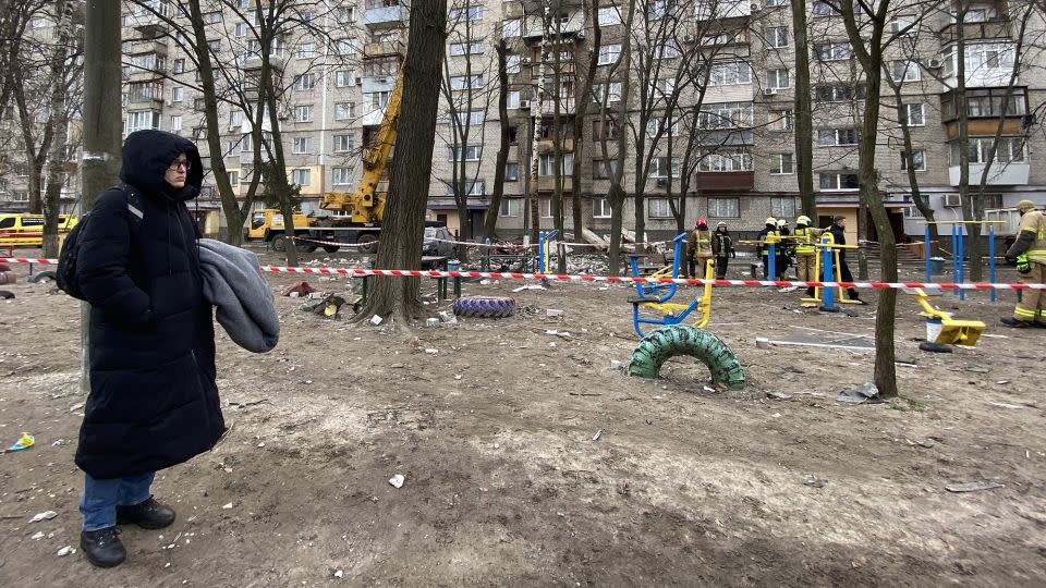 Yevhenia Tsyplionkova watches on as firefighters remove debris from where her mom’s apartment used to be. - Ivana Kottasová/CNN