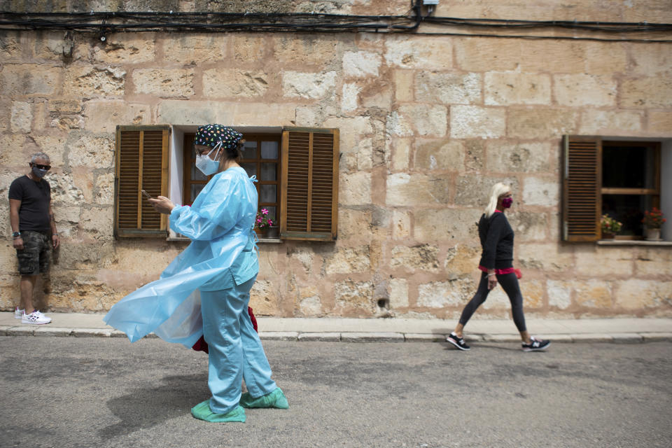 Nurse Pilar Rodríguez arrives to start visiting her patients in the town of Sa Pobla on the Spanish Balearic Island of Mallorca, Spain, Friday, April 30, 2021. Pilar Rodríguez, age 49, is one of three nurses in the town of Sa Pobla in the interior of the island to administer shots there and in nearby villages. On her rounds of the area on foot, she is welcomed amiably by elderly folk, many bound to a chair or a bed. So far, Rodríguez said she and her colleagues have vaccinated over 70 people at their homes in the rural area. They have all received the Pfizer-BioNTech vaccine, the shot leading Spain's campaign. (AP Photo/Francisco Ubilla)