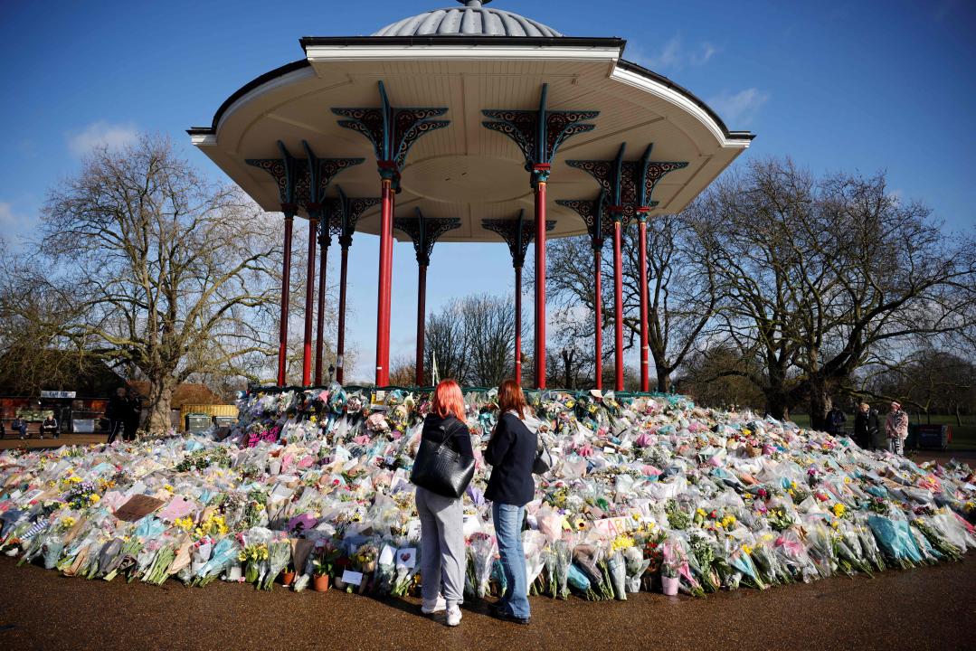 TOPSHOT - Well-wishers reflect as floral tributes and messages in honour of Sarah Everard, the missing woman whose remains were found in woodland in Kent, are displayed at the bandstand on Clapham Common in south London on March 17, 2021. - Prime Minister Boris Johnson said Wednesday Britain needed 