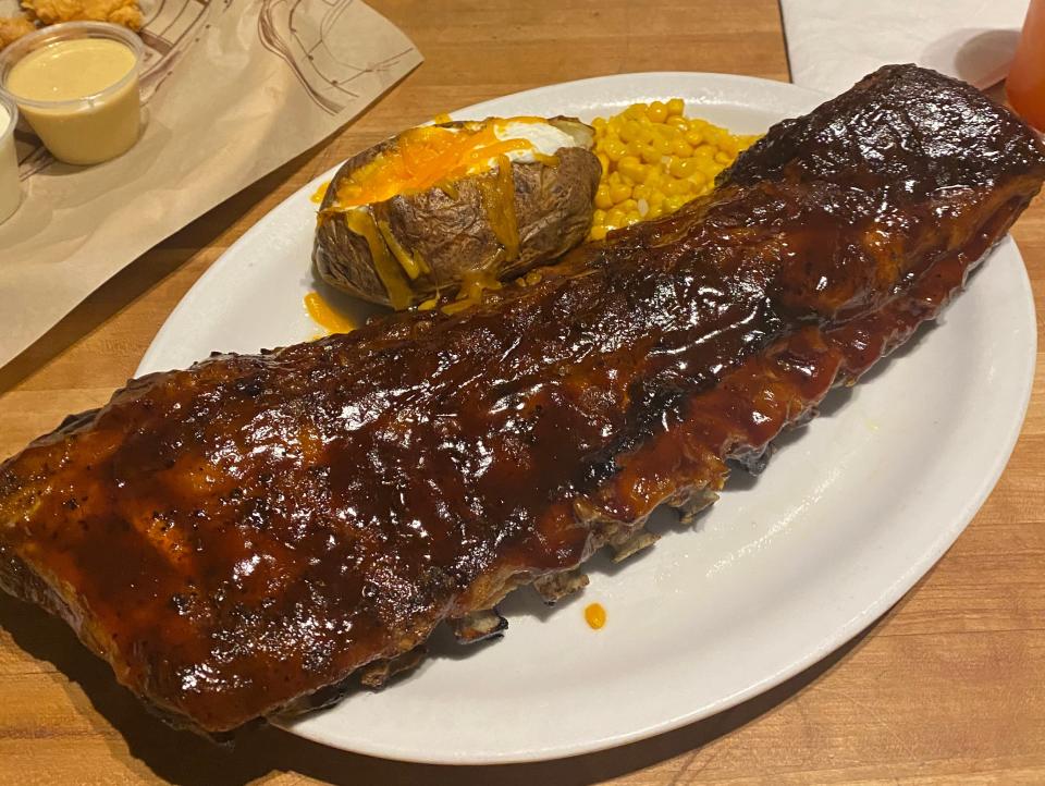 plate of ribs with a baked potato and corn