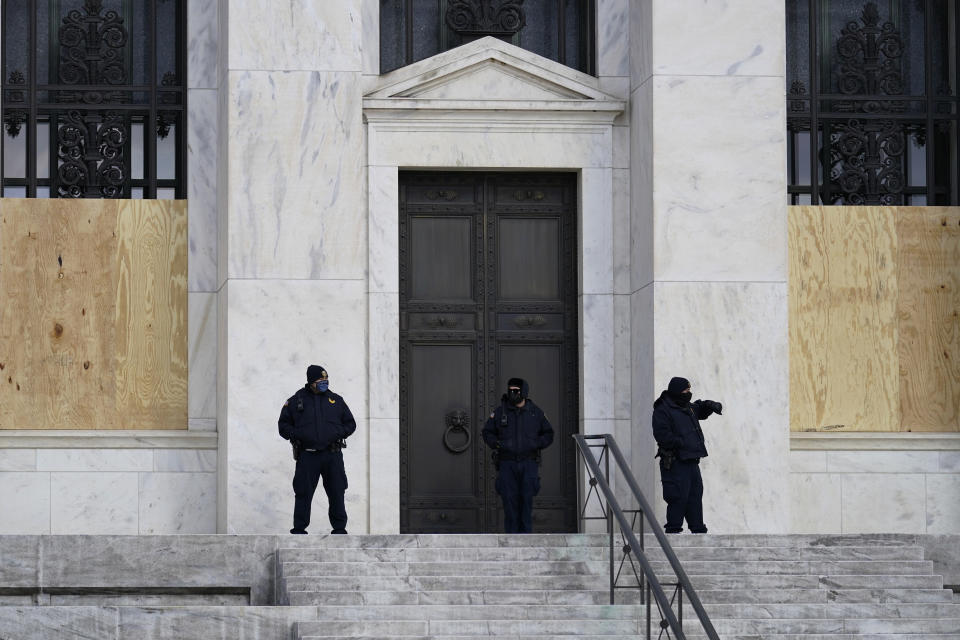 Security guards stand in front of a boarded Federal Reserve building ahead of President-elect Joe Biden's inauguration ceremony, Wednesday, Jan. 20, 2021, in Washington. (AP Photo/Gerald Herbert)